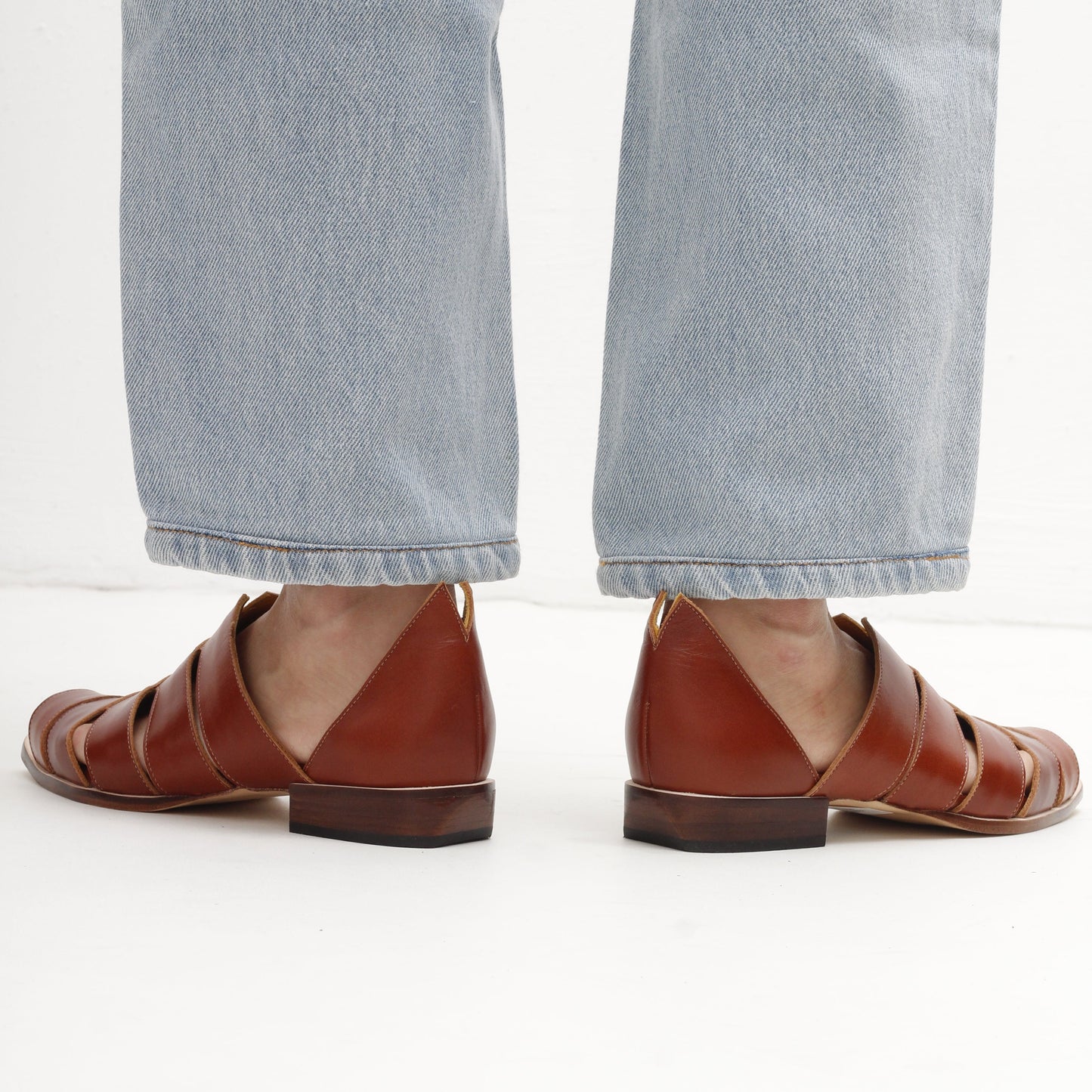 peep toe brown leather stripy smart sandals and light blue jeans on a white background