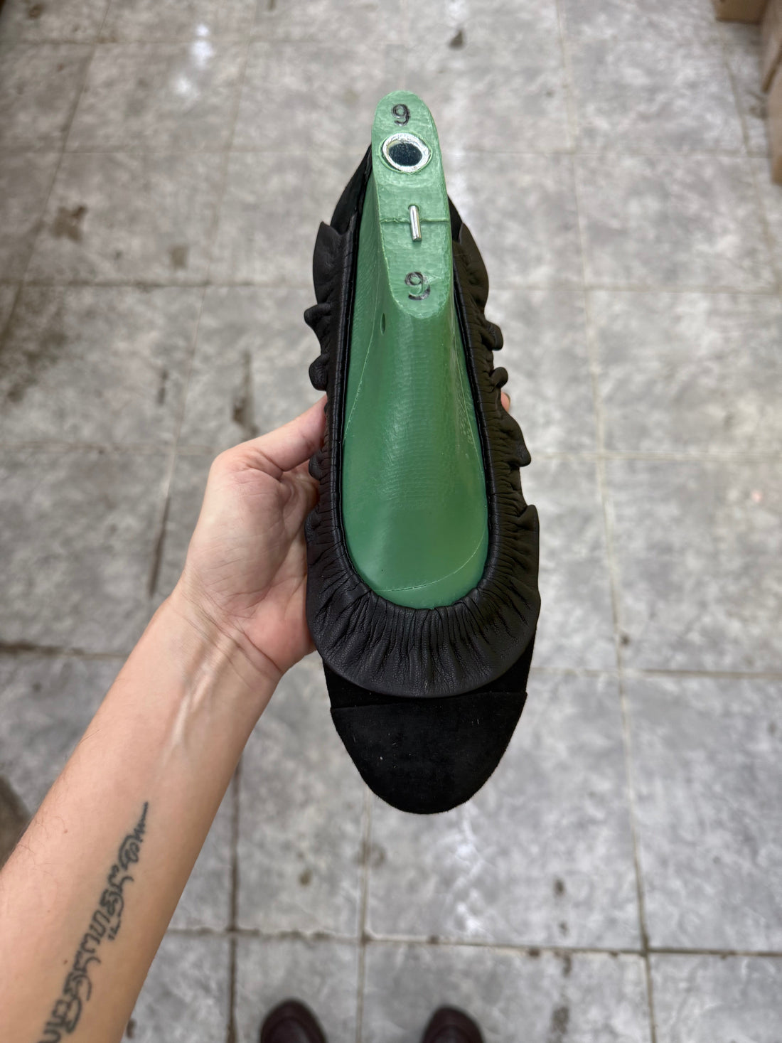 person holding handmade leather shoe in its last showing craftsmanship