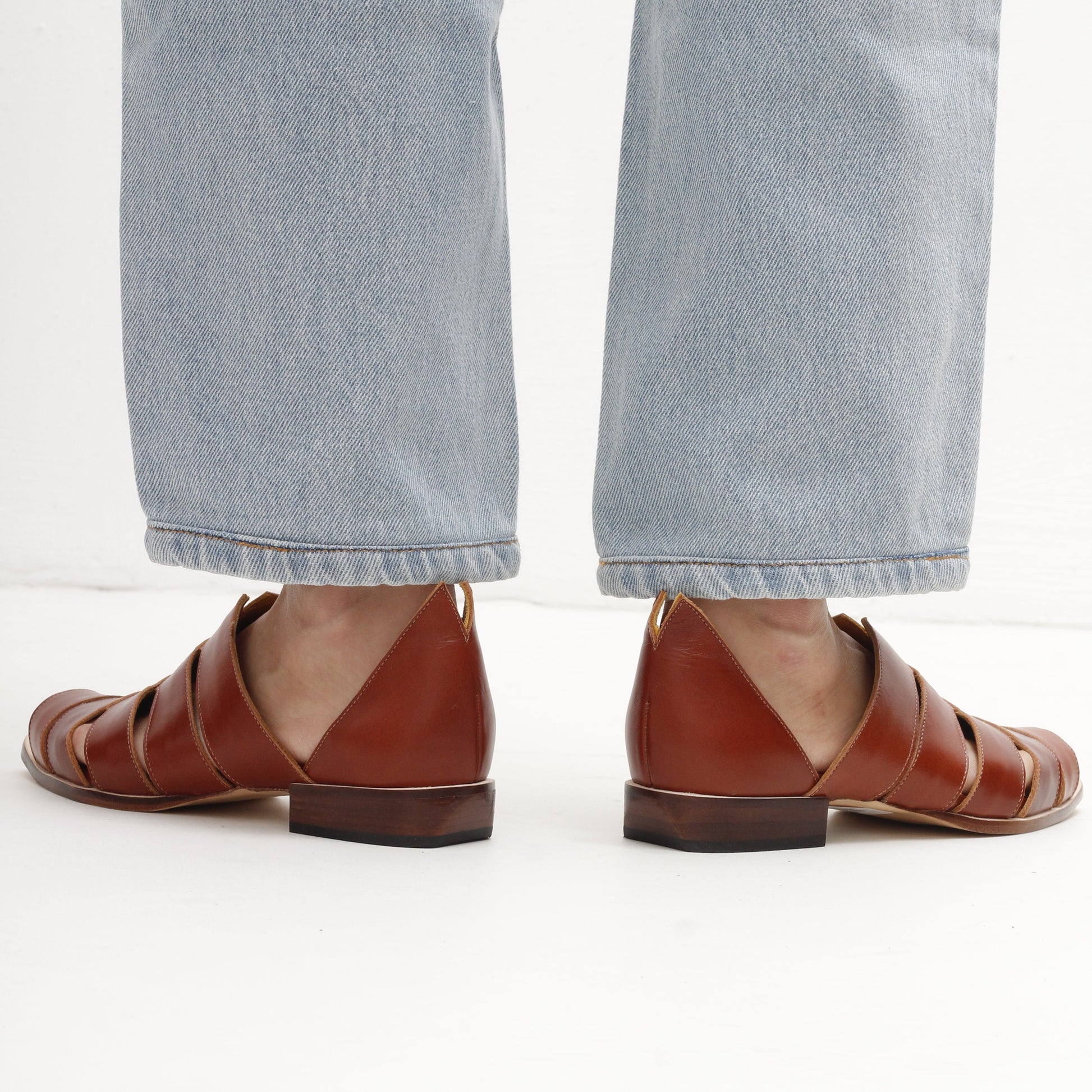 peep toe brown leather stripy smart sandals and light blue jeans on a white background