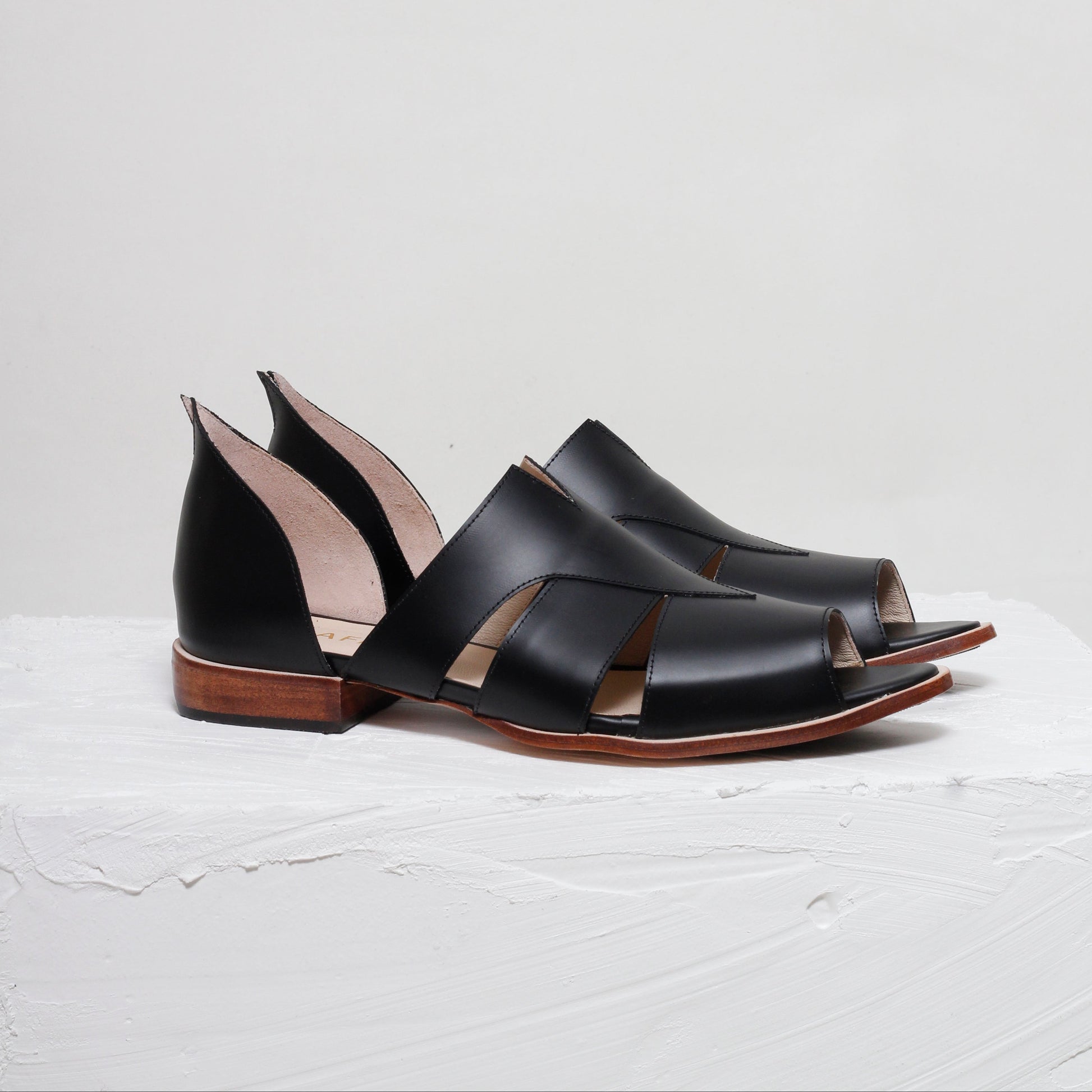 Pair of black leather sandals on a light gray background