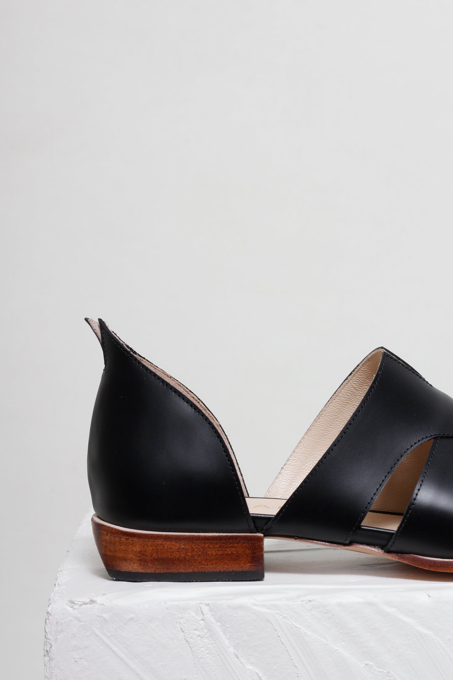 Black open-toe shoes with wooden soles on a light gray background