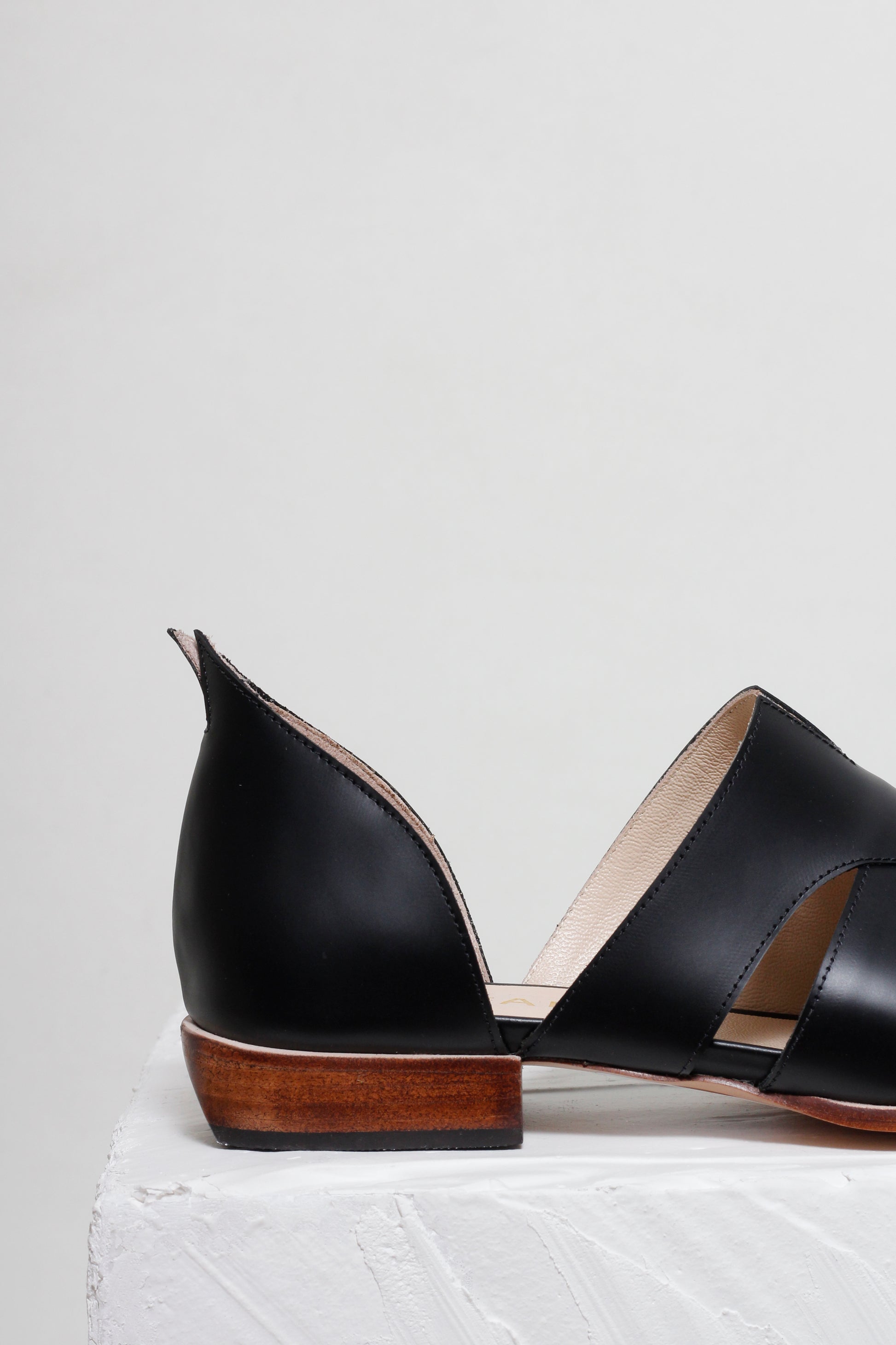 Black open-toe shoes with wooden soles on a light gray background