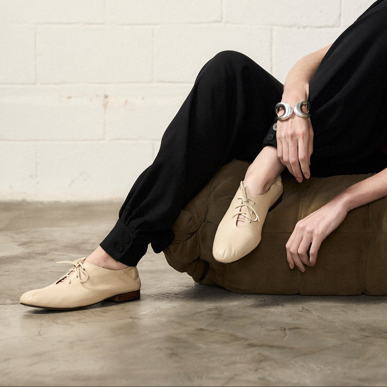 Person wearing Lila Off White Derbies by Mafalda Handmade a silver bracelet and black pants